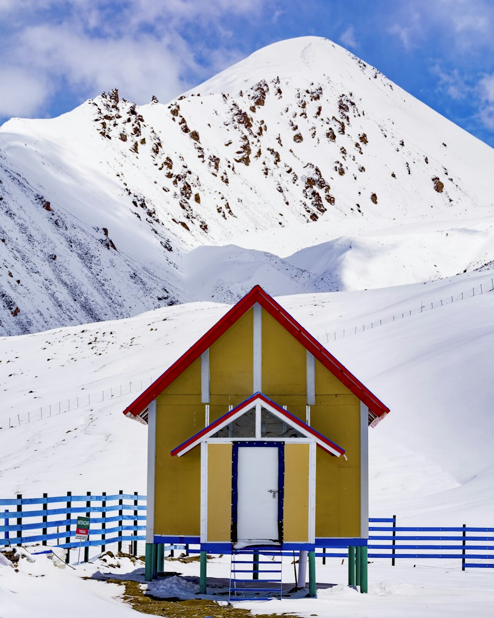 brown, white, and red hut across white mountain during daytime