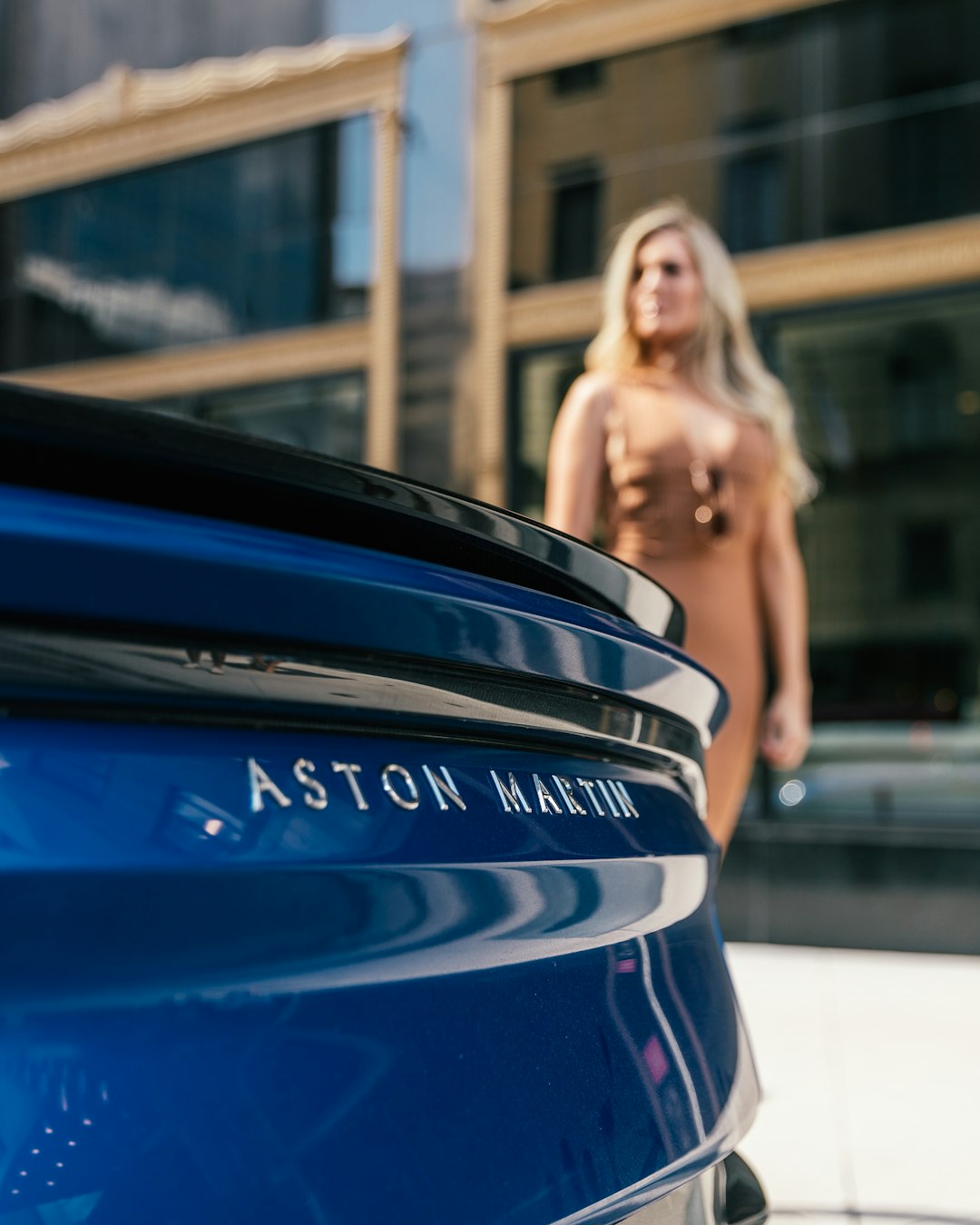 woman walking near blue Aston Martin vehicle close-up photography