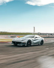 Close-up of a sleek sports car speeding on a racetrack during sunset.