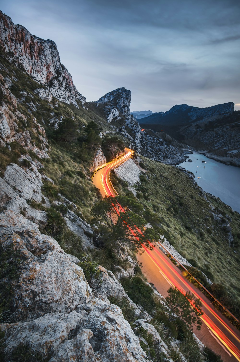 strada accanto a una scogliera vicino allo specchio d'acqua durante il giorno