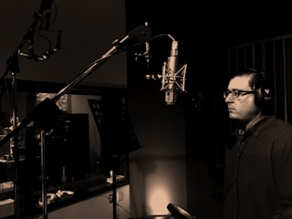 man standing in front of condenser microphone inside recording studio