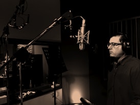 man standing in front of condenser microphone inside recording studio