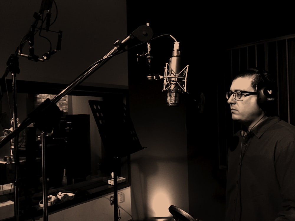 man standing in front of condenser microphone inside recording studio