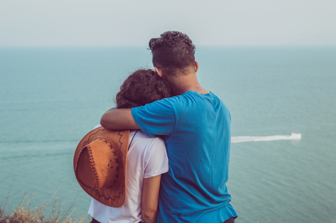 couple on top of mountain facing sea