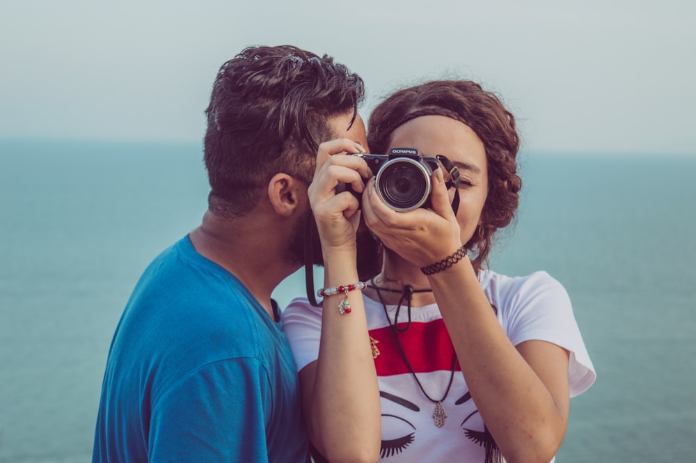 homme embrassant la joue d’une femme tout en prenant une photo