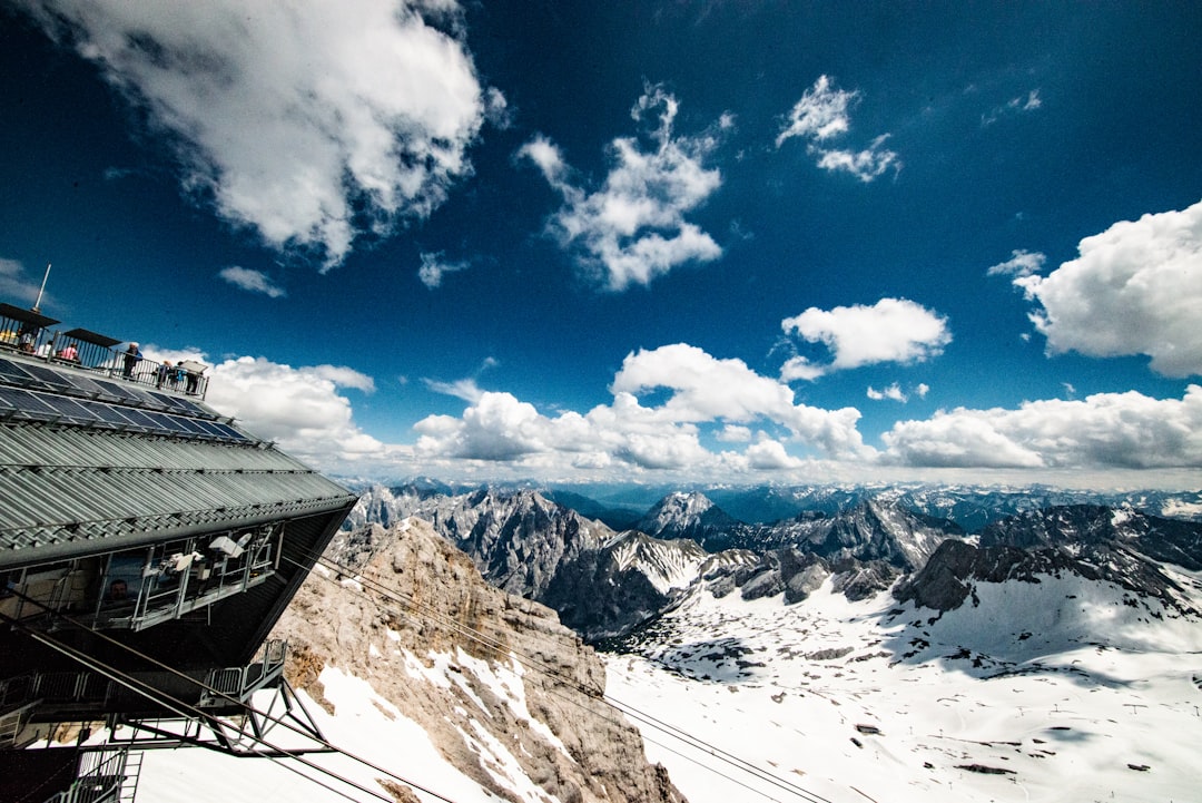 nature photography of building with cables overlooking snow-capped mountain range during daytime