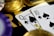 A close-up view of playing cards, specifically a Queen and a Ten of spades, surrounded by shiny gold coins and part of a poker chip, suggesting a gambling or casino theme.
