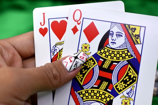 person holding queen of diamonds and jack of hearts playing cards