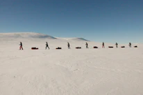 A group of happy travelers on snowshoes crossing a pristine Arctic landscape at sunset.