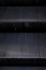 Close-up of a shiny escalator step being carefully maintained by a technician.