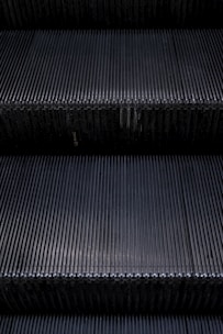 Close-up of a shiny escalator step being carefully maintained by a technician.