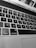 Close-up view of a laptop keyboard with black keys and white letters, including the 'option' and 'command' keys. The image is in black and white, and the laptop screen is partially visible at the top displaying some icons and part of a webpage.