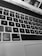 Close-up view of a laptop keyboard with black keys and white letters, including the 'option' and 'command' keys. The image is in black and white, and the laptop screen is partially visible at the top displaying some icons and part of a webpage.