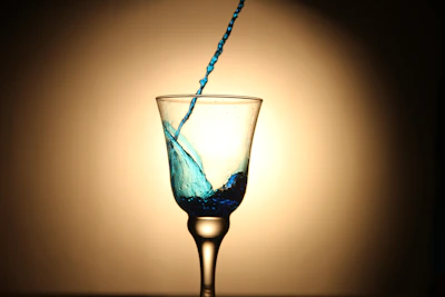An elegant wine pour featuring a glass catching the golden light, set against a midnight blue backdrop.