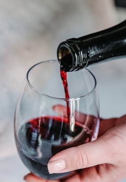 person pouring wine on clear wine glass