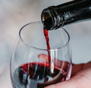 person pouring wine on clear wine glass