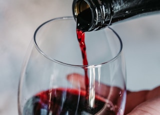 person pouring wine on clear wine glass