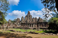 An ancient temple framed by lush tropical foliage under a bright, sunny sky.