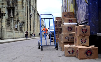 blue hand truck beside cardboard boxes
