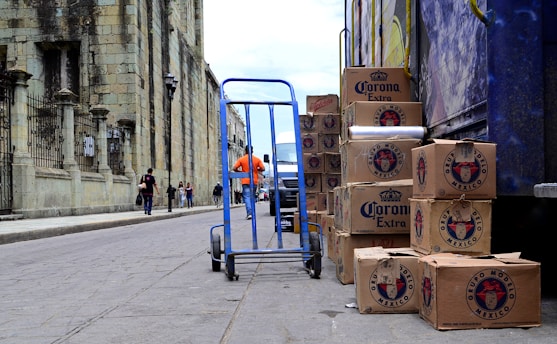blue hand truck beside cardboard boxes