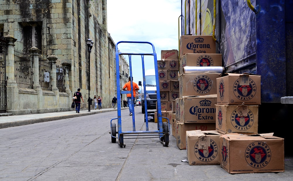 blue hand truck beside cardboard boxes