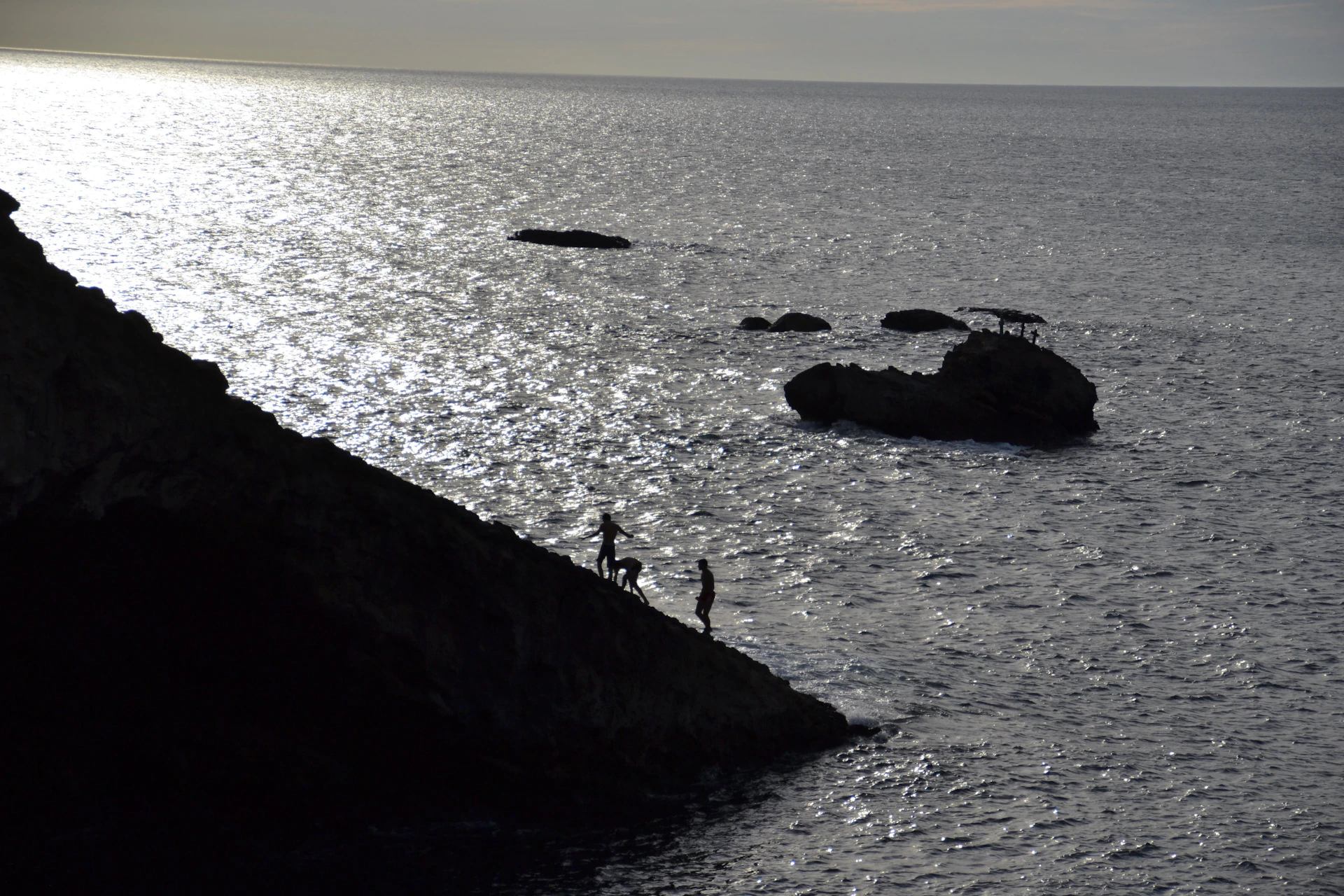 a couple of people standing on top of a cliff near the ocean