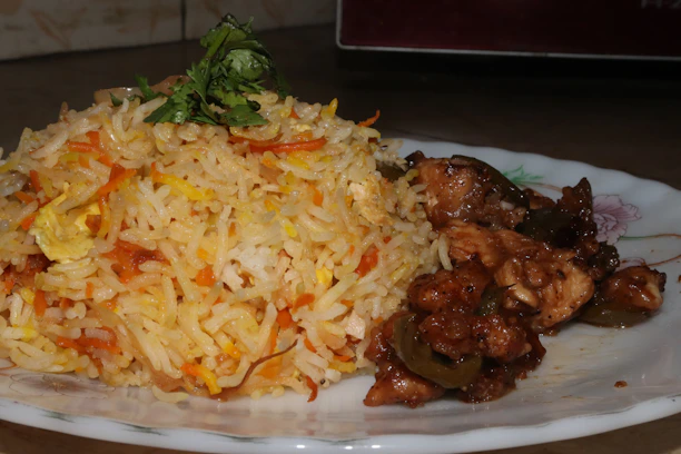 A vibrant dish of golden fried ginger chicken served with fresh herbs and steamed rice.