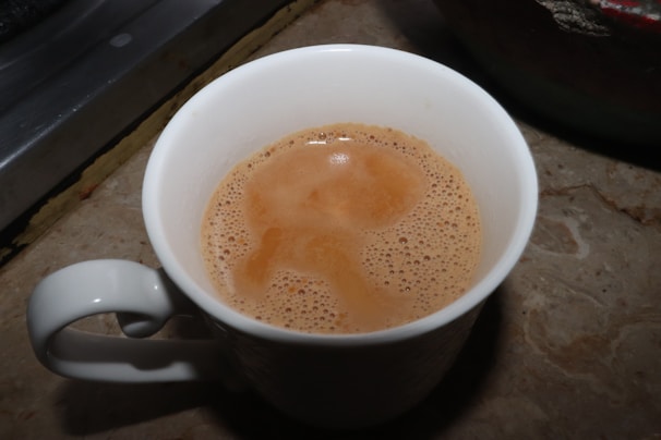 A vibrant mug filled with coffee, featuring a sleek printvibe logo on a marble countertop.