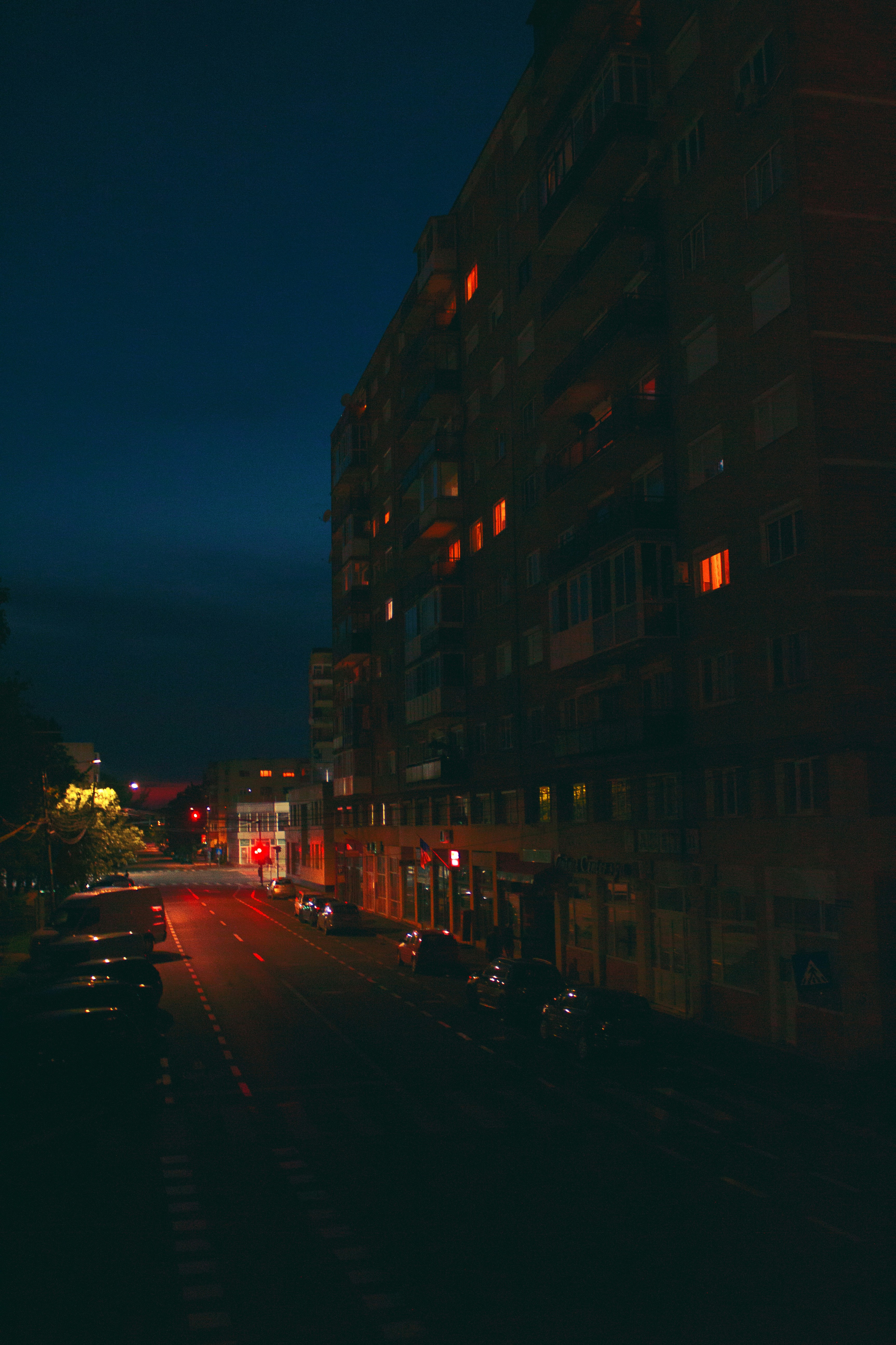 A city street at night with cars parked on the side of the road photo ...