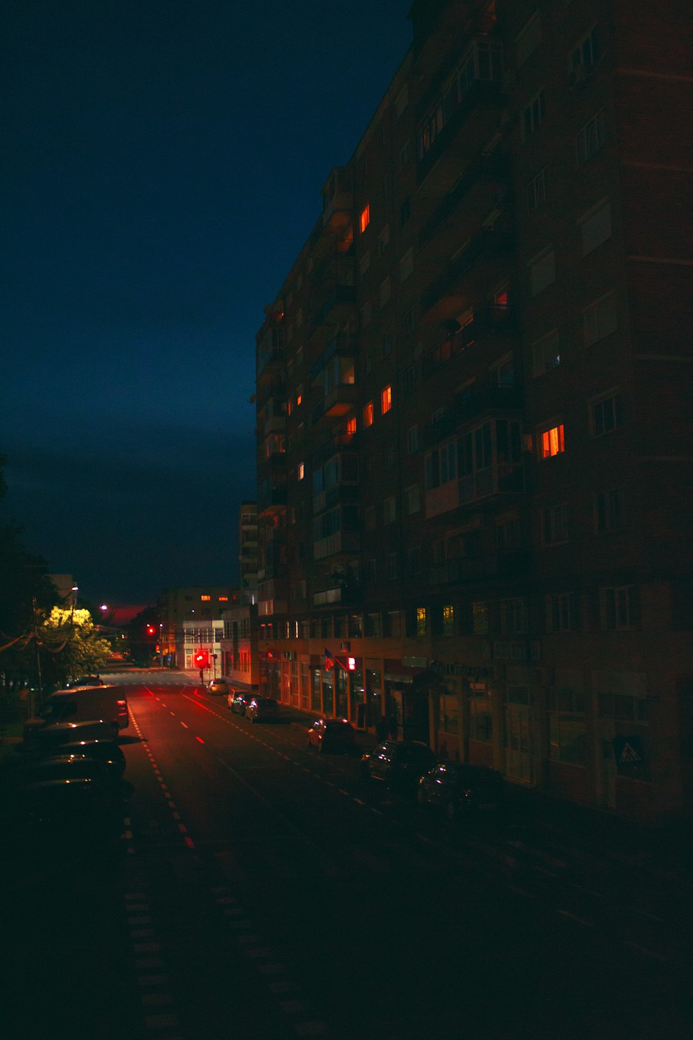 uma rua da cidade à noite com carros estacionados à beira da estrada