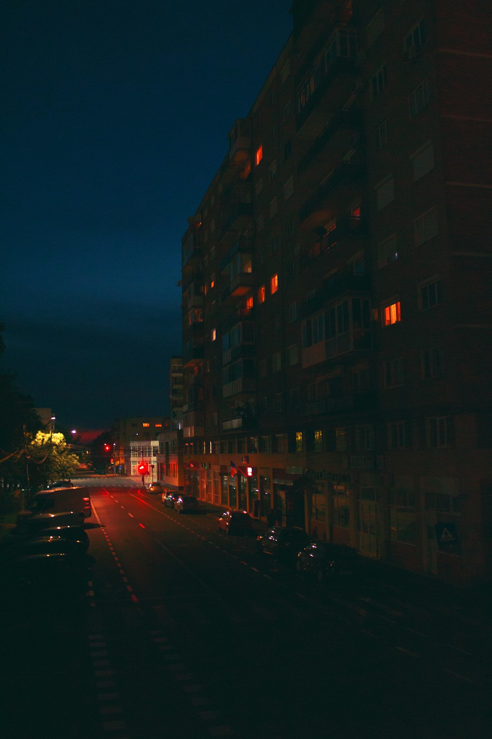 a city street at night with cars parked on the side of the road