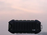 Sleek waterproof marine speaker mounted on a yacht railing with ocean background.