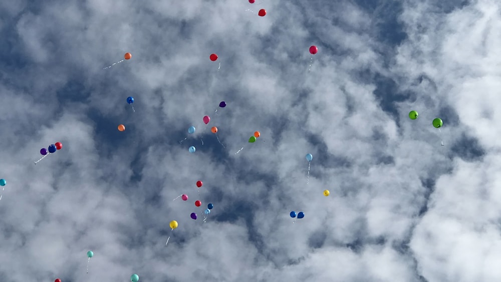 multicolored helium balloons soaring in white cloudy sky