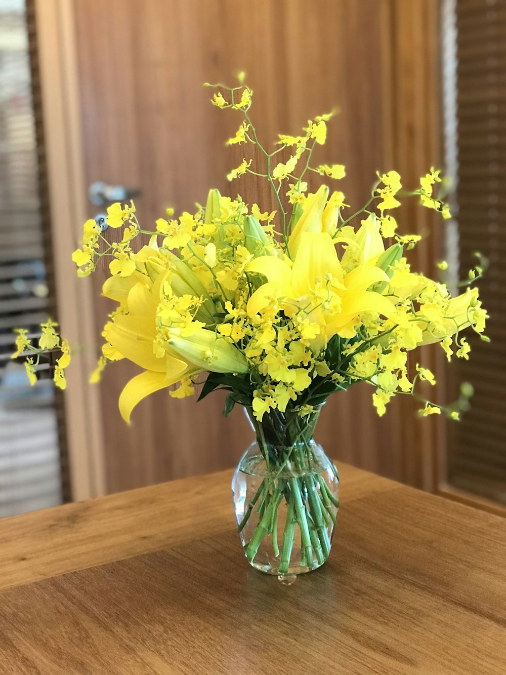 Gelbe Blütenblätter in Glasvase auf dem Tisch