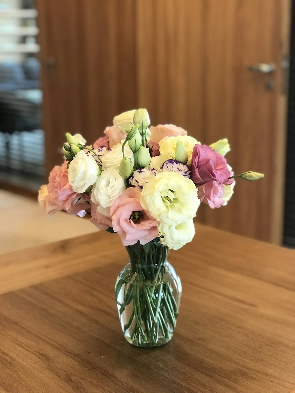 flores de rosas de colores variados en jarrón de vidrio transparente sobre mesa