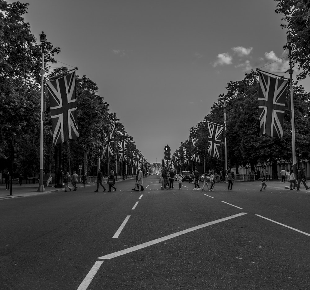 people walking on street with Union flag grayscale photo