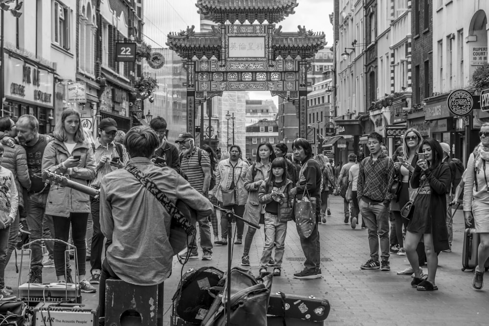 people watching man playing guitar in the street