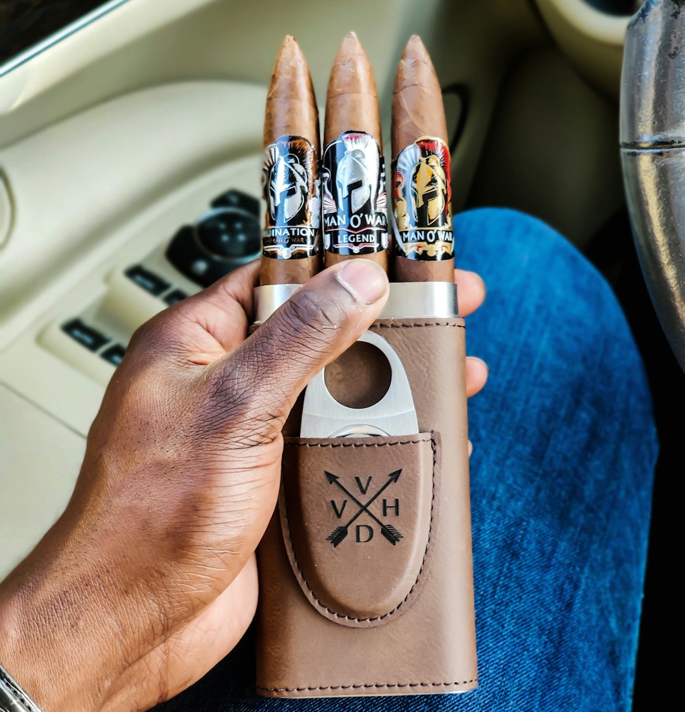 person holding brown leather cigar case