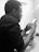 Photo of a focused technician using a tablet in front of HVAC equipment.