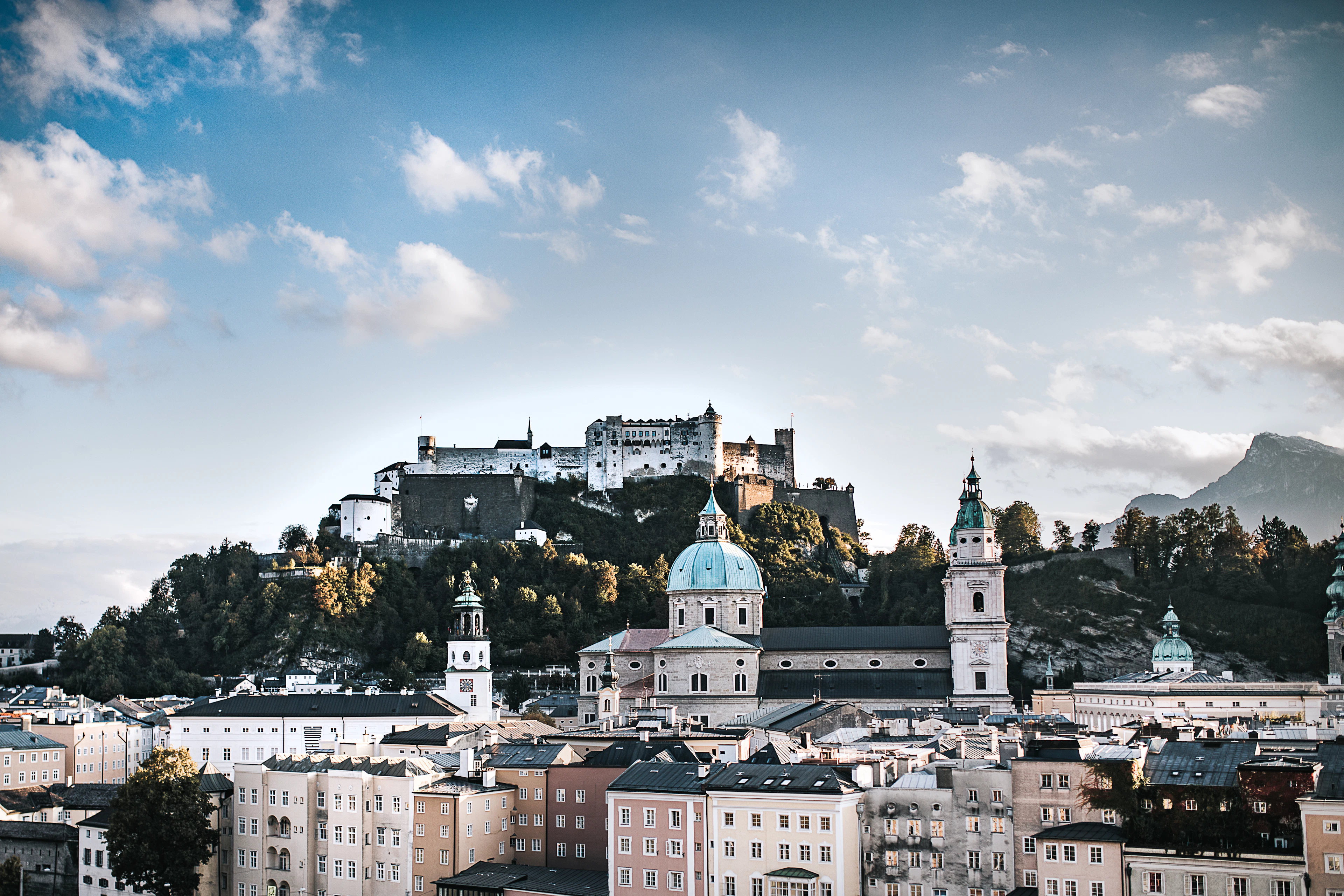 Hohensalzburg Fortress on its wooded ridge above the green dome and towers of Salzburg Cathedral