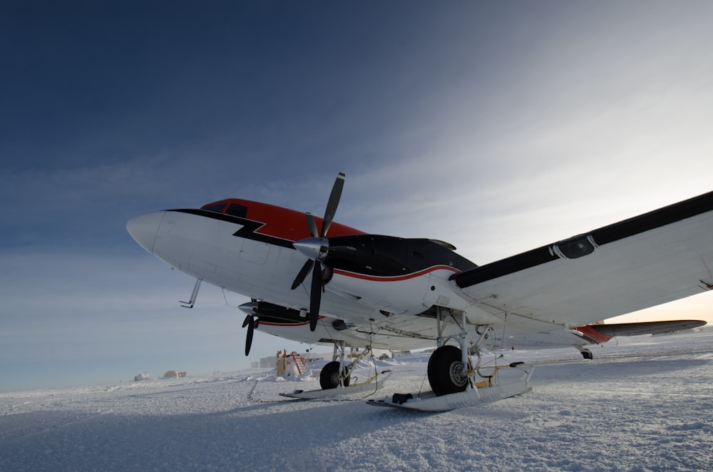 white, black, and red propeller plane on snow