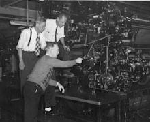 three men standing beside machine