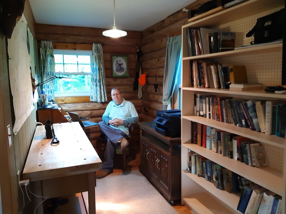 man sitting near bookcase