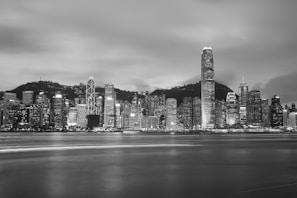 A monochrome photo of a cityscape at night, emphasizing light and shadow.