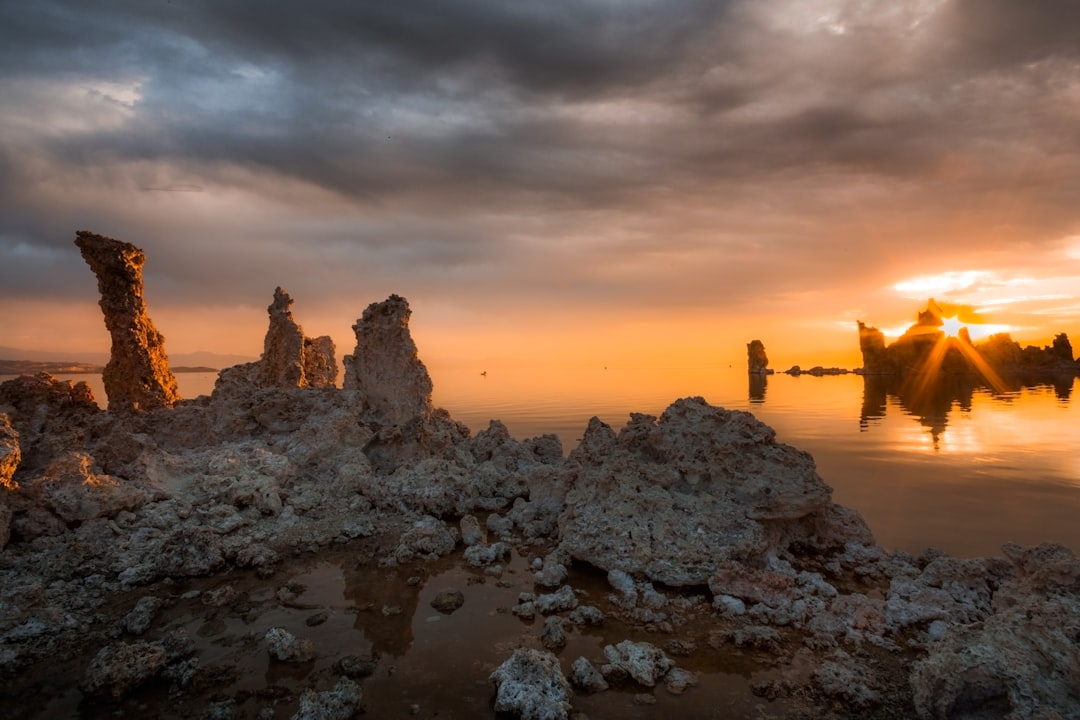 rock formations near calm body of water, Mono Rising - The onset of stormy weather created reflections of light and colo