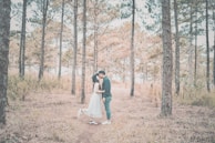 Couple exchanging vows in an intimate outdoor wedding surrounded by tall forest trees.