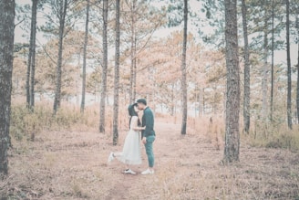 Couple exchanging vows in an intimate outdoor wedding surrounded by tall forest trees.