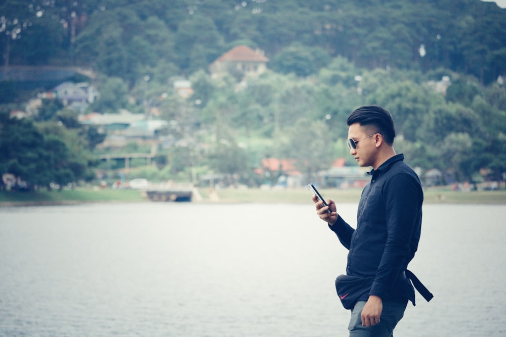 man using phone near river