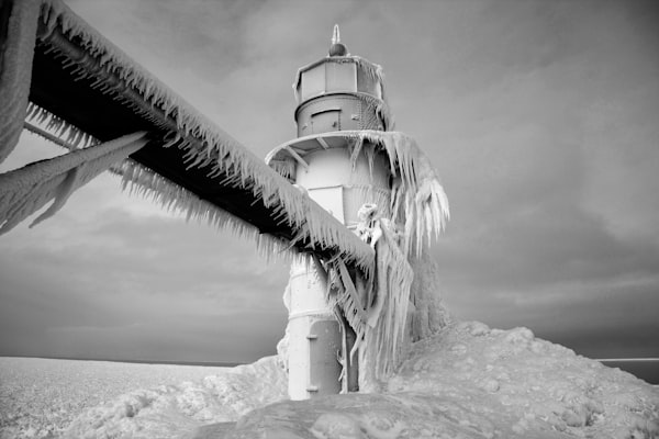 a lighthouse and a walkway frozen in winter snow and ice