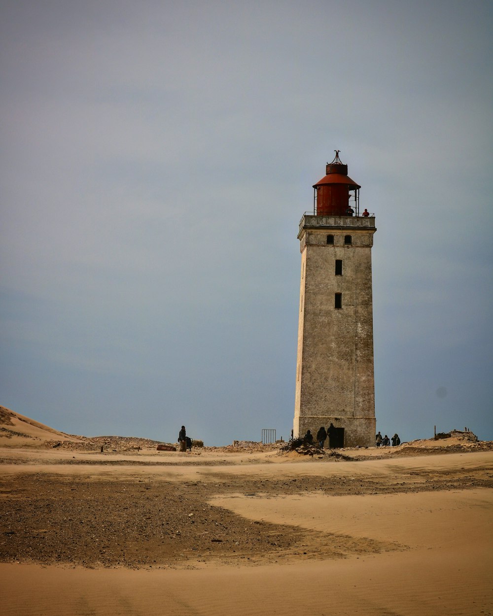 Faro blanco y rojo en playa de arena marrón